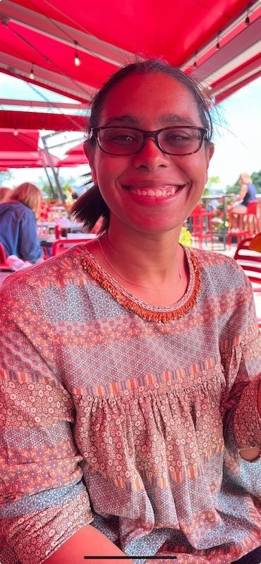 Maya sitting and smiling in an outdoor venue